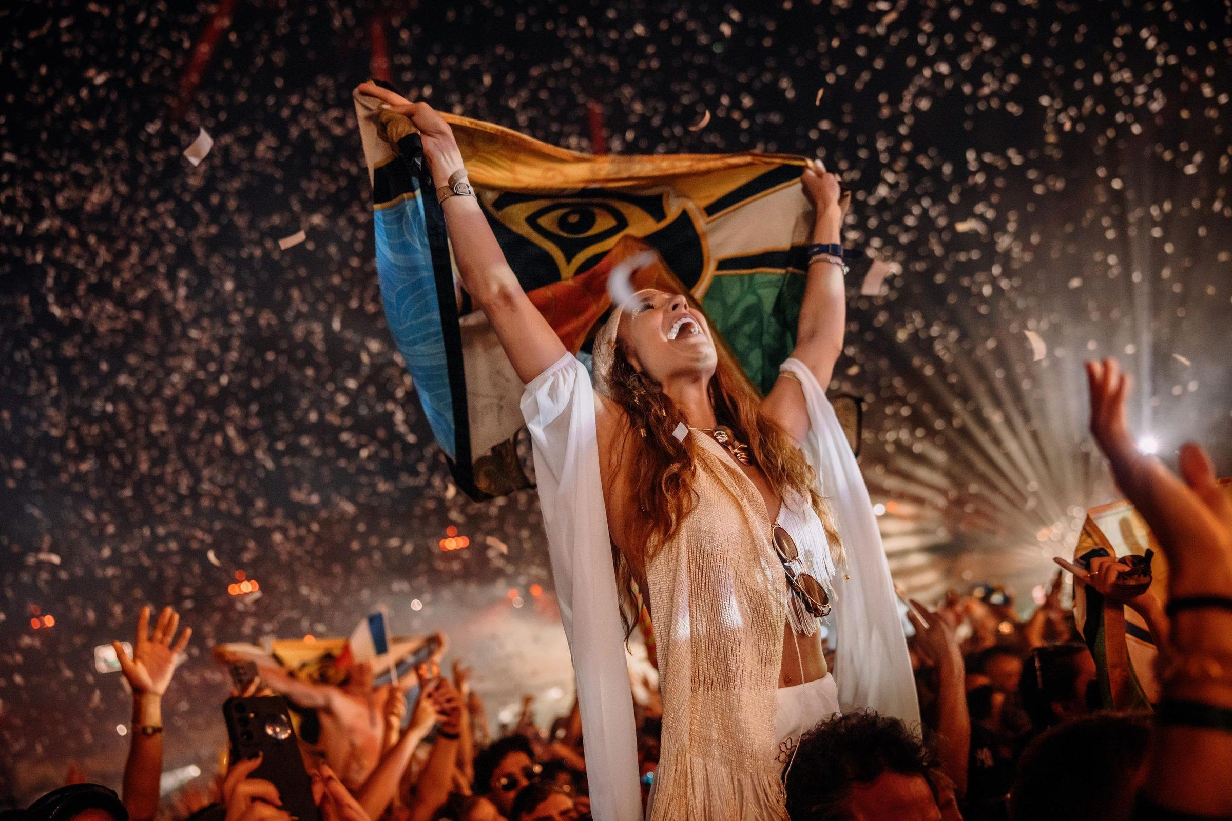 Fan celebrando con la bandera de Tomorrowland bajo una lluvia de confeti